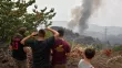 Des habitants regardent la fumée s'élever d'une colline près du village de Kourkouli, dans le nord de l'île d'Eubée, le 5 août 2021, alors que les pompiers grecs luttent pour maîtriser deux incendies majeurs qui font rage près d'Olympie et sur l'île d'Eubée. LOUISA GOULIAMAKI / AFP


