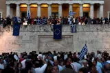 Des manifestants pro-Europe agitent des drapeaux grecs et européens devant le parlement à Athènes. Ils espèrent ainsi que Tsipras dise oui à la proposition des créanciers. Sur un mur de la ville, des tagueurs ont enterré l'euro. © AFP.


