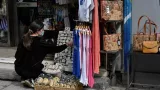 Une femme ajuste des objets exposés à l'extérieur d'un magasin à Athènes, au premier jour de la réouverture, le 5 avril 2021. LOUISA GOULIAMAKI/AFP


