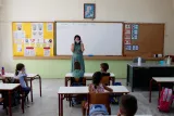 Une enseignante explique à ses élèves comment utiliser le masque contre la propagation du Covid-19, photo d'illustration prise le 14 septembre 2020, à Athènes (Grèce). PHOTO / THANASSIS STAVRAKIS / POOL VIA REUTERS.


