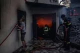 Des habitants et des pompiers essayent d'éteindre le feu dans une maison à Kryoneri, près d'Athènes, le 26 juillet 2025  -  Angelos TZORTZINIS - Athènes (AFP)