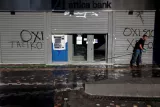 Un homme nettoie la chaussée devant une banque à Athènes encore fermée. Image: Archives/Reuters


