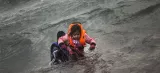 Après être tombés de leur canot pneumatique au moment de débarquer, un homme porte une petite fille pour l'aider à atteindre le rivage de l'île de Lesbos, dimanche 3 janvier. Crédits photo : Santi Palacios/AP


