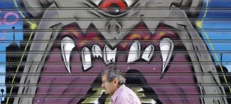 Un homme passe devant la devanture fermée d'un magasin dans le centre-ville d'Athènes. Crédits photo : CHRISTIAN HARTMANN/REUTERS


