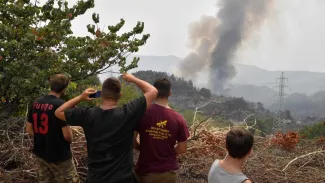 Grèce : les pompiers bataillent contre deux incendies préoccupants à Olympie et Eubée Des habitants regardent la fumée s'élever d'une colline près du village de Kourkouli, dans le nord de l'île d'Eubée, le 5 août 2021, alors que les pompiers grecs luttent pour maîtriser deux incendies majeurs qui font rage près d'Olympie et sur l'île d'Eubée. LOUISA GOULIAMAKI / AFP