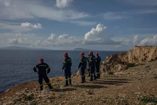 Des pompiers envoyés en renfort sur l'île d'Amorgos regardent au loin l'île d'Anydros, considérée comme l'épicentre de l'essaim de tremblements de terre, sur l'île grecque d'Amorgos, dans la mer Egée, le 15 février 2025. ANGELOS TZORTZINIS / AFP