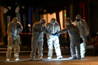 Des experts de la police grecque en combinaison de protection cherchent des preuves après l'explosion d'une bombe devant les bureaux d'Hellenic Train à Athènes, le 11 avril 2025.