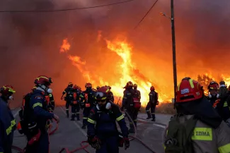 Des pompiers s'efforcent d'éteindre un incendie de forêt, attisé par des vents violents, qui a conduit à des messages d'évacuation près du village de Karyes, sur l'île de Chios, en Grèce, le 22 juin 2025. KONSTANTINOS ANAGNOSTOU / REUTERS