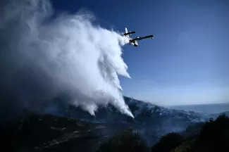 Un avion Canadair de lutte contre les incendies largue de l'eau sur un feu de forêt, près de Thymari, au sud-est d'Athènes, le 26 juin 2025 en Grèce - Aris MESSINIS - Thymari (AFP)