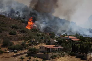 Des flammes s'élèvent près des maisons alors qu'un incendie de forêt fait rage, dans le village de Thimari, près d'Athènes, en Grèce, le 26 juin 2025. STELIOS MISINAS / REUTERS