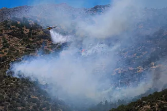 Un hélicoptère largue de l'eau sur un incendie de forêt qui s'est déclaré à Ierapetra, sur l'île grecque de Crète, le 3 juillet 2025  -  Costas METAXAKIS - Ierapetra (AFP)