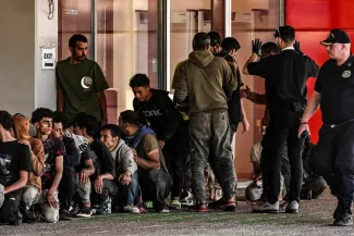 Des migrants sont rassemblés par des gardes-côtes grecs après avoir débarqué d'un cargo, dans le port de Lavrio, au sud d'Athènes, le 10 juillet 2025. ARIS MESSINIS / AFP