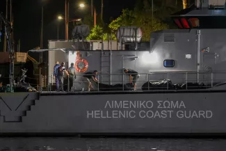 Des hommes transfèrent des sacs mortuaires contenant les corps de migrants décédés après le naufrage de leur bateau en pleine mer au large de la Grèce, à bord d'un navire des garde-côtes helléniques dans le port de Kalamata, en Grèce, le 14 juin 2023. STELIOS MISINAS / REUTERS