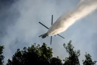 Un hélicoptère de lutte contre les incendies largue de l’eau sur un feu de forêt dans la région de Porto Germeno (Grèce), le 2 août 2026. ANGELOS TZORTZINIS/AFP