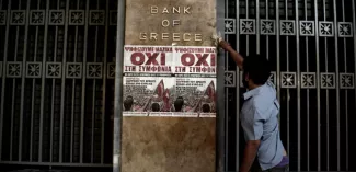 5 questions que vous vous posez sur le référendum grec Un homme colle une affiche en faveur du non au référendum grec, sur le mur du siège de la Banque de Grèce, le 3 juillet 2015. (ARIS MESSINIS/AFP)