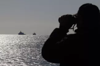Grèce : sauvetage en cours après le naufrage d'un bateau chargé de migrants Un garde-côtes grec observe des bateaux au large de la Crète, le 27 novembre 2014.