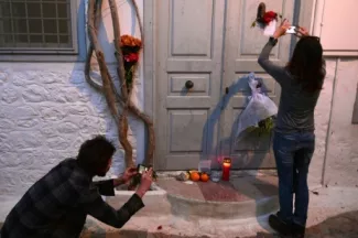 Des gens prennent en photos les messages et les fleurs déposées en mémoire de Leonard Cohen qui possédait une maison sur l'île grecque d'Hydra, le 11 novembre 2016


