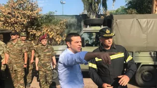 Incendies en Grèce : Tsipras s'engage à lutter contre les constructions illégales Le Premier ministre grec Alexis Tsipras (c) en déplacement sur les lieux d'un incendie meurtrier, le 30 juillet 2018 à Mati, à l'est d'Athènes