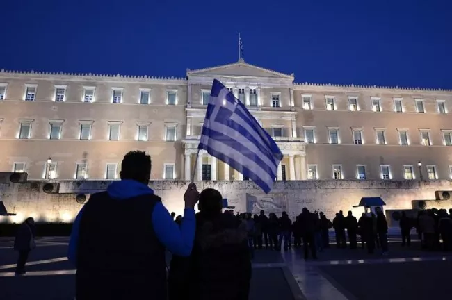 Un homme tient un drapeau grec devant le parlement à Athènes le 20 février 2015 (Photo Louisa Gouliamaki. AFP)


