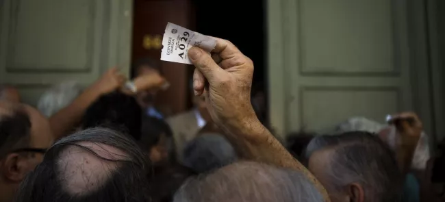 Les retraités devaient prendre un ticket, vendredi à la Banque nationale grecque, pour toucher leur pension avec un maximum de 120 euros. Crédits photo : Emilio Morenatti/AP


