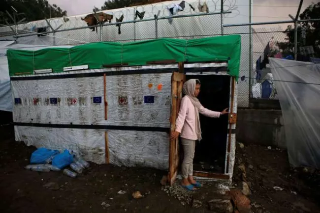 Une jeune fille se tient à l’entrée d’un abri de fortune dans un camp de réfugiés et de migrants à Moria, sur l’île de Lesbos, le 22 novembre. ELIAS MARCOU / REUTERS


