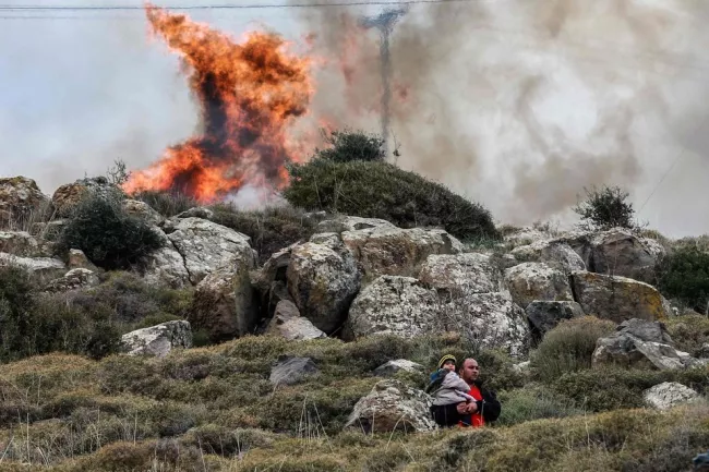 Un migrant et son enfant lors de heurts pendant les manifestations aux abords du camps de Kara Tepe sur l'île de Lesbos, lundi.



