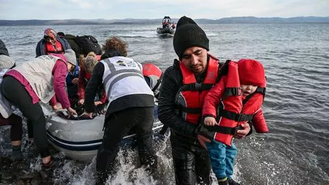 Les membres d'une ONG aident des réfugiés afghans à débarquer d'un canot pneumatique alors qu'il atterrit sur l'île grecque de Lesbos le 28 février 2020


