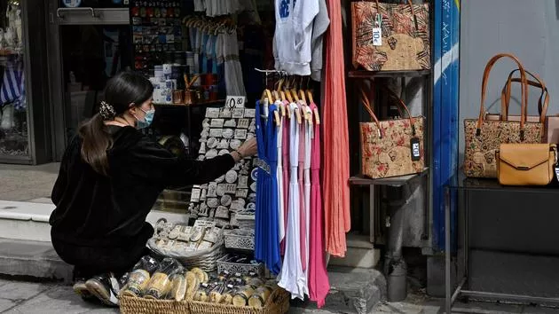 Une femme ajuste des objets exposés à l'extérieur d'un magasin à Athènes, au premier jour de la réouverture, le 5 avril 2021. LOUISA GOULIAMAKI/AFP


