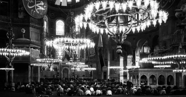 La prière de l'Asr orientée près du mirhab logé dans l'abside du bâtiment. Durant la cérémonie, les femmes sont interdites d'accès à l'espace principal. Le public non-musulman peut observer à distance. L'espace est ensuite rouvert à tous jusqu'à la… — © Nicolas Brodard


