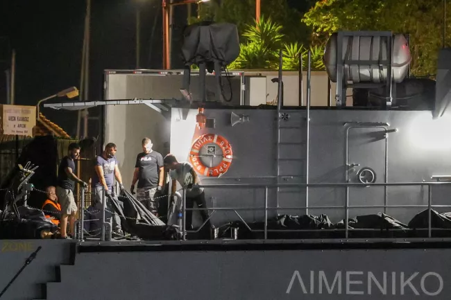 Des hommes transfèrent les sacs mortuaires des migrants morts, après le chavirement de leur bateau en pleine mer, au large de la Grèce, à bord d'un navire des gardes-côtes dans le port de Kalamata, en Grèce, le 14 juin 2023. STELIOS MISINAS / REUTERS
