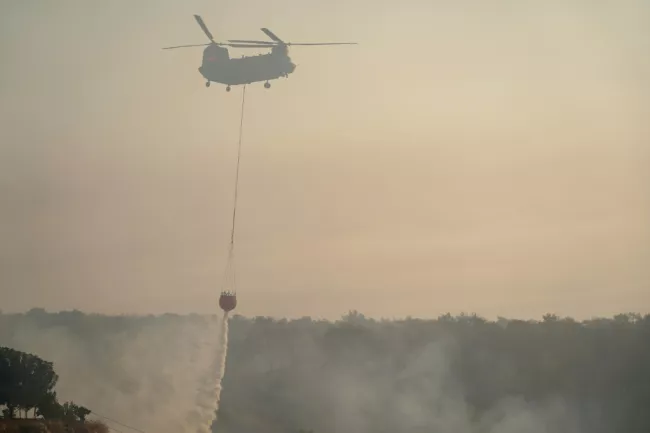 Un hélicoptère participe aix opérations pour éteindre les flammes après un feu de forêt dans le village chypriote de Souni, dans la province de Limassol, le 24 juillet 2025  -  Etienne TORBEY - Soúni (AFP)