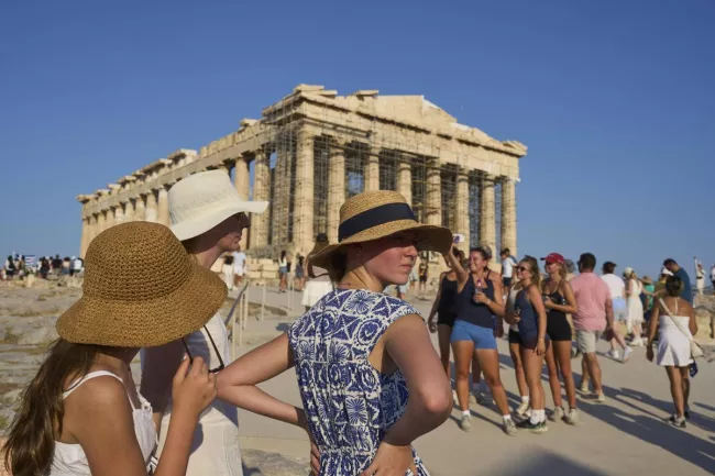Des touristes coiffés de chapeaux se tiennent devant le temple du Parthénon, sur la colline de l'Acropole, pendant une vague de chaleur à Athènes, le vendredi 25 juillet 2025. PETROS GIANNAKOURIS/AP/SIPA