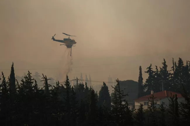 Un hélicoptère de lutte contre les incendies largue de l'eau lors d'un feu de forêt dans le village de Drosopigi, près d'Athènes, le 26 juillet 2025. ALKIS KONSTANTINIDIS / REUTERS