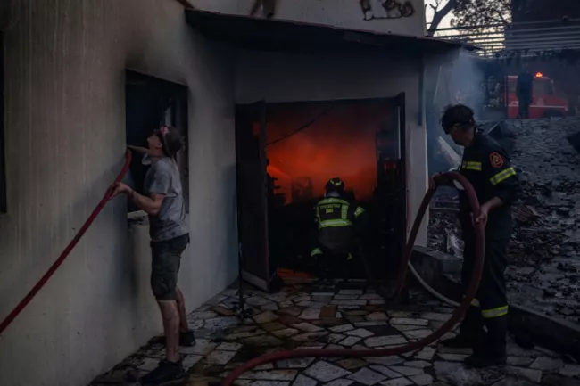 Des habitants et des pompiers luttent contre les flammes à Kryoneri, près d'Athènes, le 26 juillet 2025  -  Angelos TZORTZINIS - Athènes (AFP)