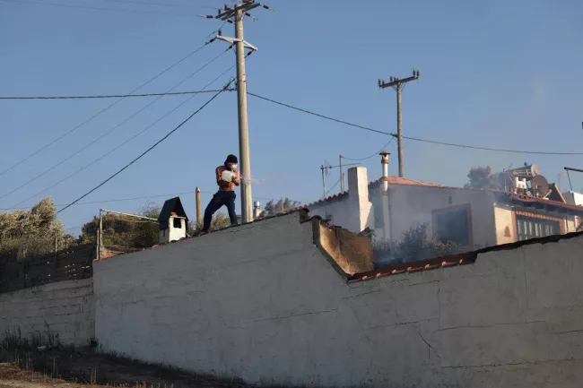 Un habitant de Keratea, près d'Athènes, tente d'éteindre un incendie, le 8 août 2025. STELIOS MISINAS / REUTERS