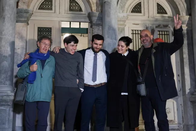 Sean Binder (2ᵉ à gauche) en compagnie d'autres travailleurs humanitaires engagés dans le sauvetage de réfugiés, après leur acquittement, à Mytilène, en Grèce, le 15 janvier 2026. ELIAS MARCOU/REUTERS