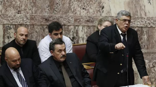 Debout, Nikos Michaloliakos, président de l'Aube dorée, au Parlement, le 30 mars. Crédits photo : Petros Giannakouris/AP


