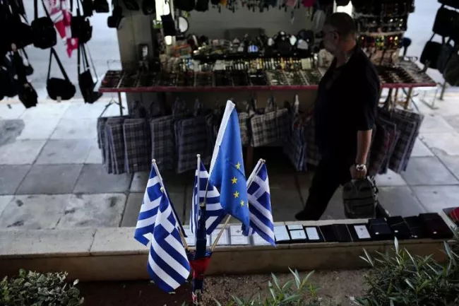 Trois drapeaux grecs et un drapeau européen près du port du Pirée à Athènes, le 14 juin 2015 (Photo ANGELOS TZORTZINIS. AFP)


