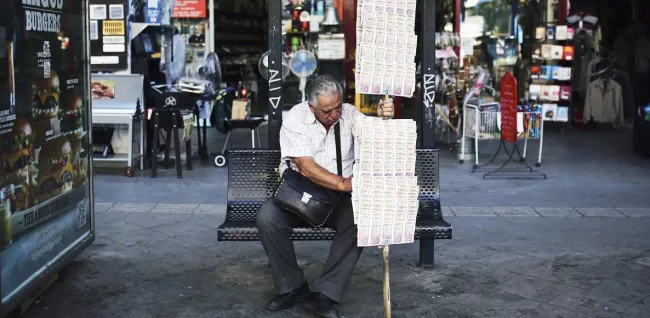 Un vendeur de ticket de loterie dans les rues, le 3 juin, à Athènes. Crédits photo : ANGELOS TZORTZINIS/AFP


