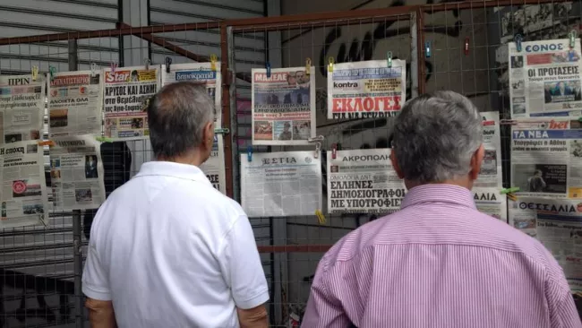 Deux hommes scrutent les unes de journaux grecs, titrant tous sur les négociations avec les créanciers du pays (Crédit: Tristan QUINAULT-MAUPOIL/LE FIGARO)


