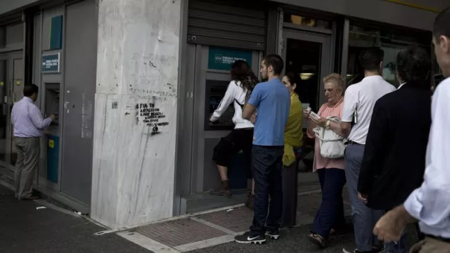 Des Grecs font la queue devant un distributeur de billets, vendredi à Athènes. Crédits photo : Petros Giannakouris/AP


