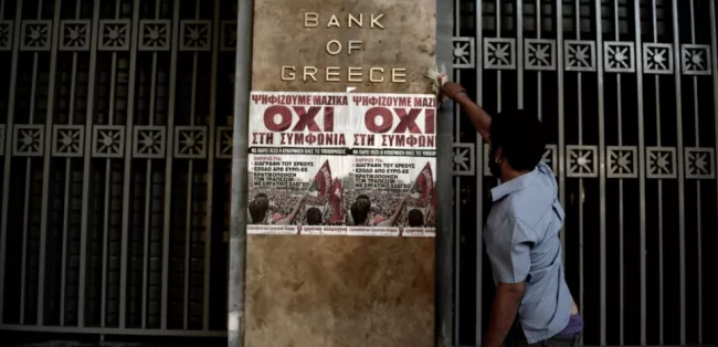 Un homme colle une affiche en faveur du non au référendum grec, sur le mur du siège de la Banque de Grèce, le 3 juillet 2015. (ARIS MESSINIS/AFP)


