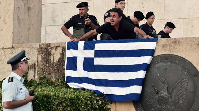 Un manifestant brandit, le 13 juillet 2015 le drapeau grec lors d'une manifestation à Athènes opposée à l'accord financier conclu à Bruxelles


