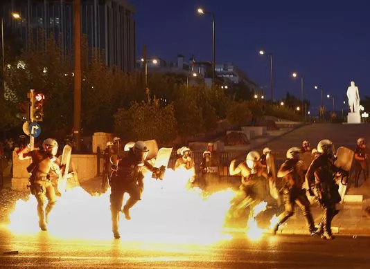 Des policiers anti-émeutes évitent la flamme d'un engin explosif à Athènes, le 15 juillet.


