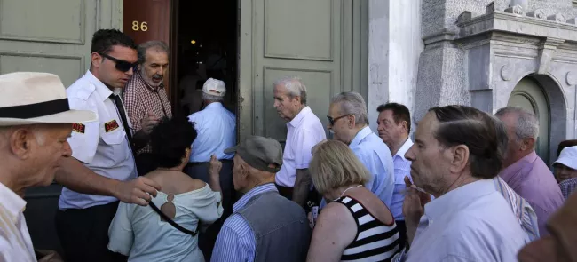 Les premiers clients, la plupart des retraités, font la queue, lundi, devant une succursale de la Banque nationale de Grèce à Athènes. Crédits photo : Thanassis Stavrakis/AP


