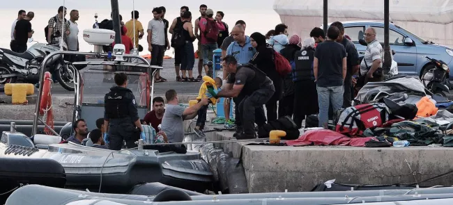 Des migrants syriens interceptés en mer sont débarqués sur le port de Kos, le 17 août en Grèce. Crédits photo : LOUISA GOULIAMAKI/AFP


