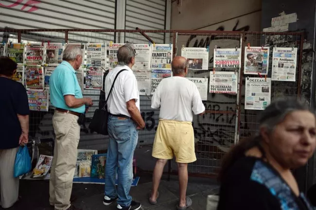 Vendredi matin à Athènes, des Grecs lisent les titres de la presse quotidienne. (Photo Louisa Gouliamaki. AFP)


