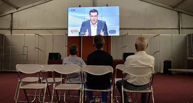 Pourtant de courte durée, la campagne électorale ne mobilise pas les foules. Quelques hommes regardent le débat télévisé diffusé mercredi soir sur les télévisions grecques. - AFP/ LOUISA GOULIAMAKI


