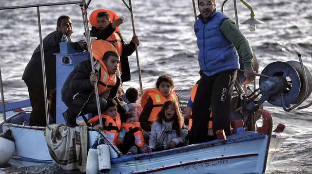 Des pêcheurs embarquent des réfugiés sur leur bateau au large de l'île de Lesbos en Grèce, le 30 octobre 2015



