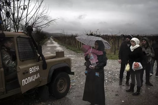 Une famille de réfugiés syriens, qui vient de franchir la frontière grecque à Idomeni, face à la police macédonienne, le 27 novembre.


